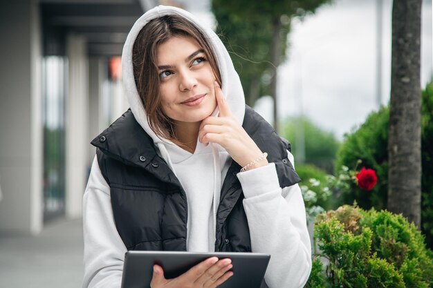 Aantrekkelijke jonge vrouw die een tablet buiten houdt