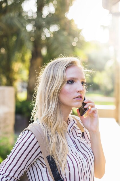 Aantrekkelijke jonge vrouw die op mobiele telefoon in openlucht spreekt