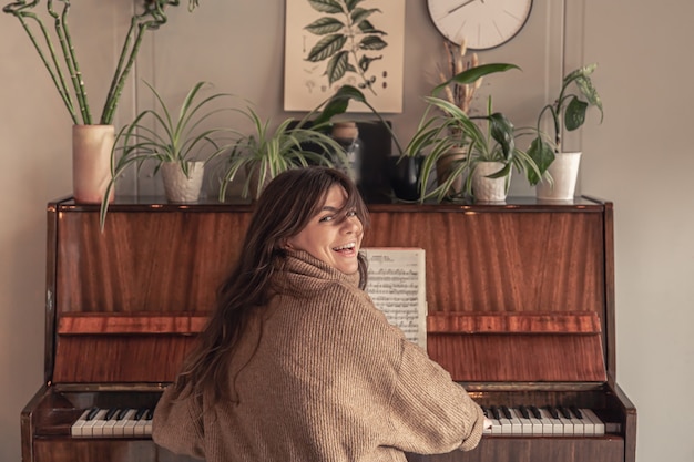 Aantrekkelijke jonge vrouw die thuis piano speelt