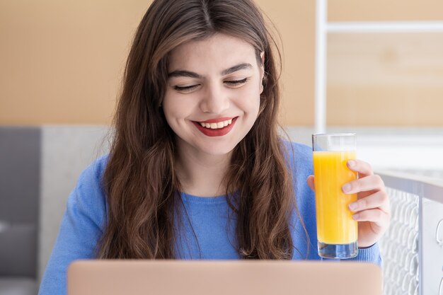 Aantrekkelijke jonge vrouw in een blauwe trui werkt op een laptop in een café