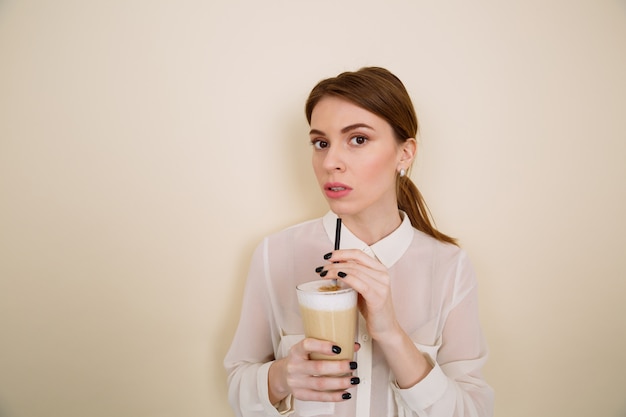 Aantrekkelijke jonge vrouw koffie latte drinken uit glas met stro