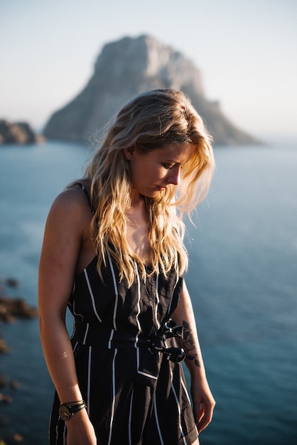 Gratis foto aantrekkelijke jonge vrouw met blonde haren staande aan zee