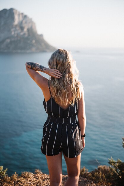 Aantrekkelijke jonge vrouw met blonde haren staande aan zee
