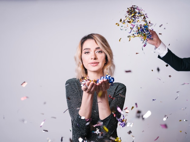 Aantrekkelijke jonge vrouw met confetti in de buurt van hand opgooien klatergoud