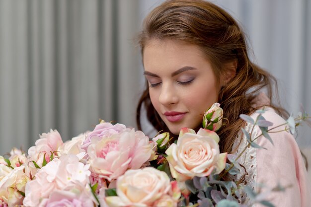 Aantrekkelijke jonge vrouw met een boeket van honderden bloemen brengt tijd thuis door.