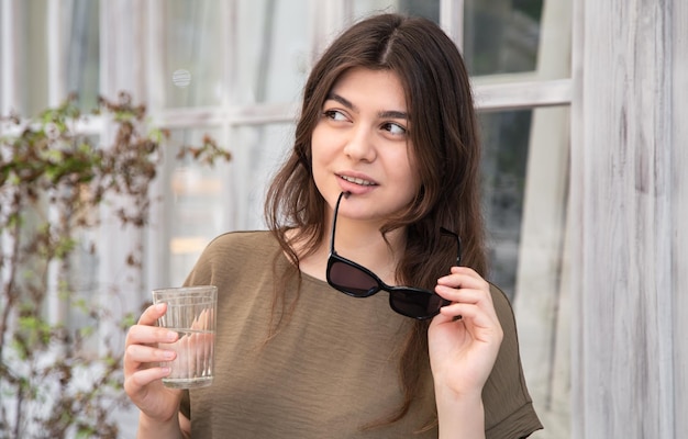 Aantrekkelijke jonge vrouw met een glas water met zonnebril