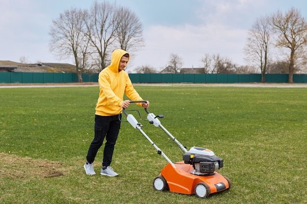 Gratis foto aantrekkelijke jongeman gras trimmen met een snijder