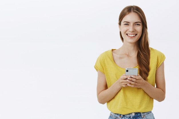 Aantrekkelijke lachende vrouw met behulp van mobiele telefoon, sms-bericht op applicatie of sociaal netwerk