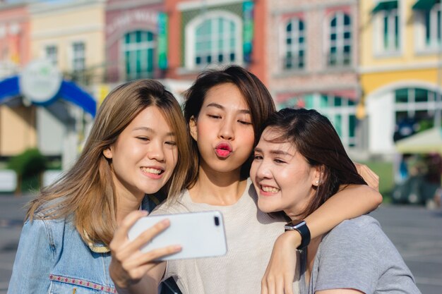 Aantrekkelijke mooie Aziatische vriendenvrouwen die een smartphone gebruiken