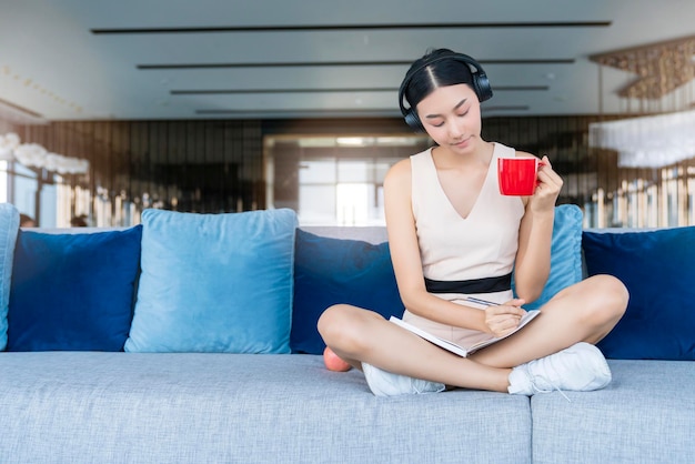 Aantrekkelijke mooie aziatische vrouwelijke smart casual ontspannen genieten van werken vanuit huis socail afstand nemen van quarantaine op sofa aziatische vrouwelijke geluk met privé-moment werken op sofa home achtergrond