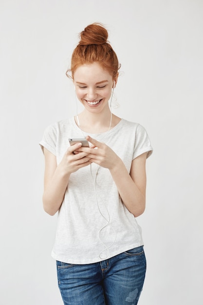 Aantrekkelijke redhead vrouw met sproeten glimlachen die telefoon bekijkt.