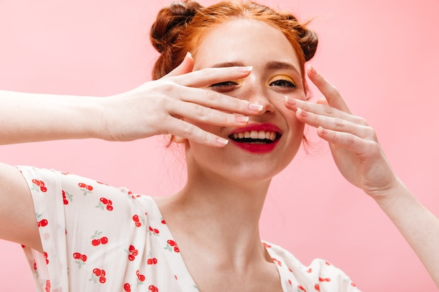 Aantrekkelijke roodharige vrouw bedekt haar gezicht met haar handen. schot van groenogige vrouw met roze lippen op geïsoleerde achtergrond.