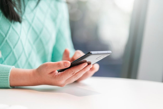 Aantrekkelijke smart casual Aziatische vrouwelijke hand chat aan het typen met behulp van smartphone telecommunicatie positieve houding glimlach in café casualsmart bedrijfseigenaar ondernemer werken met smartphone in café