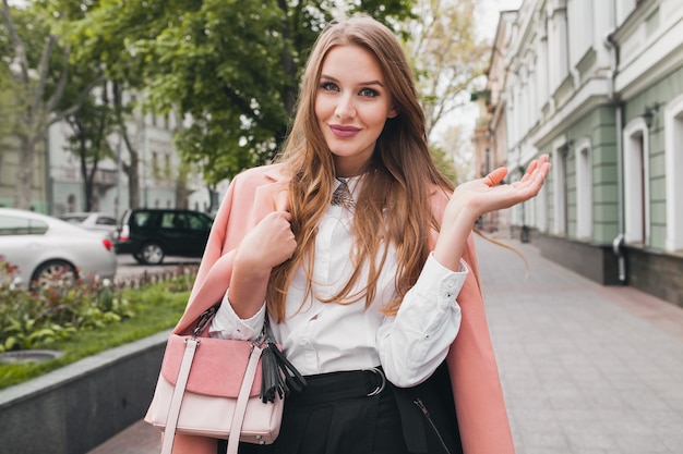 Aantrekkelijke stijlvolle lachende vrouw lopen stad straat in roze jas lente modetrend bedrijf portemonnee, elegante stijl