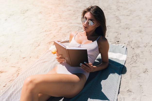 Aantrekkelijke vrouw die van lezing op strand geniet