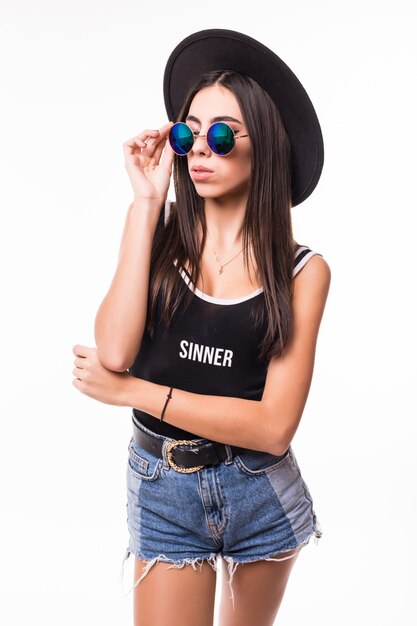 Aantrekkelijke vrouw in de zwarte hoed en zonnebril van t-shirtjeans borrels het stellen.