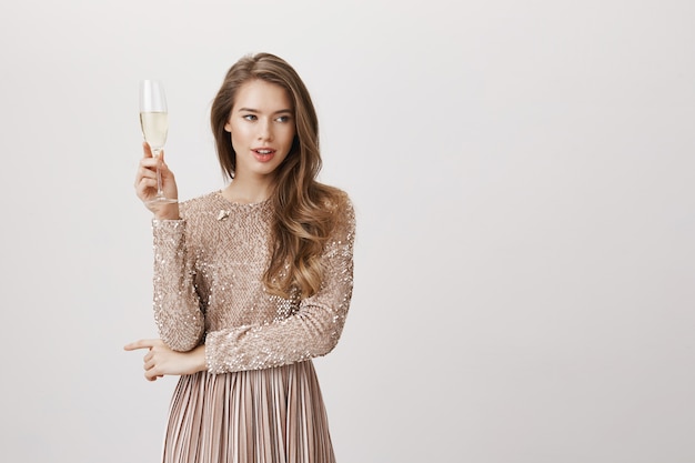 Aantrekkelijke vrouw in het glas champagne van de avondjurkholding
