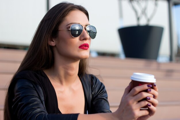 Aantrekkelijke vrouw koffie drinken en op de trap zitten