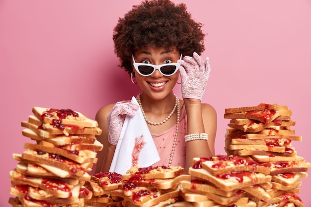 Gratis foto aantrekkelijke vrouw met afro-haar, omringd door boterhammen met pindakaasgelei