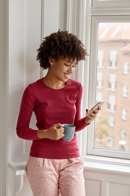 aantrekkelijke vrouw poseren met mobiele telefoon in haar huis