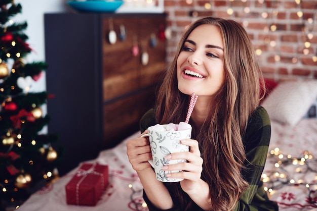 Aantrekkelijke vrouw zittend op bed en drinken