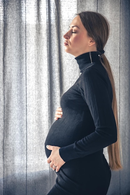 Gratis foto aantrekkelijke zwangere vrouw in het interieur van de kamer bij het raam