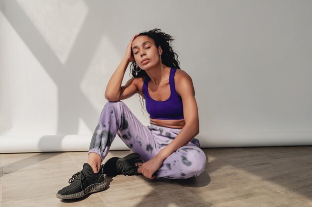 Aantrekkelijke zwarte Afro-Amerikaanse vrouw in stijlvolle hipster fitness outfit op achtergrond