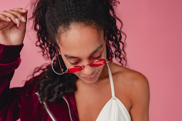 Aantrekkelijke zwarte Afro-Amerikaanse vrouw in stijlvolle outfit op roze achtergrond