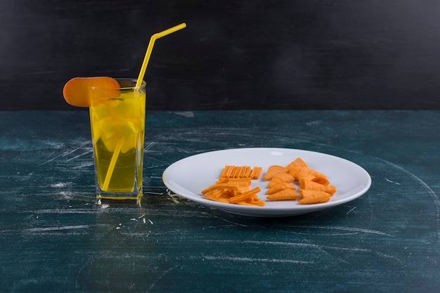 Aardappelchips in tomatensaus in een witte plaat met een glas sap