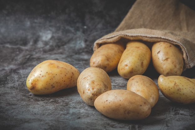 Aardappelen gieten uit zakken op grijze vloer