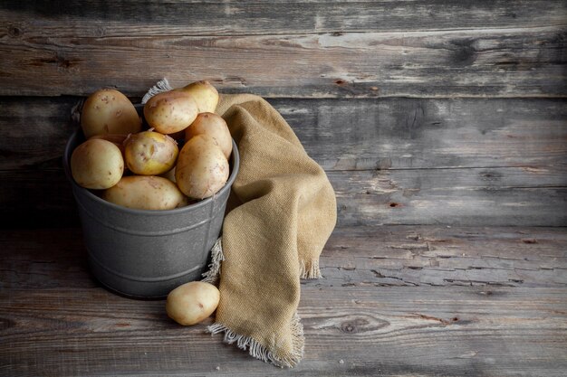 Aardappelen in een grijs emmer zijaanzicht op een donkere houten ruimte als achtergrond voor tekst