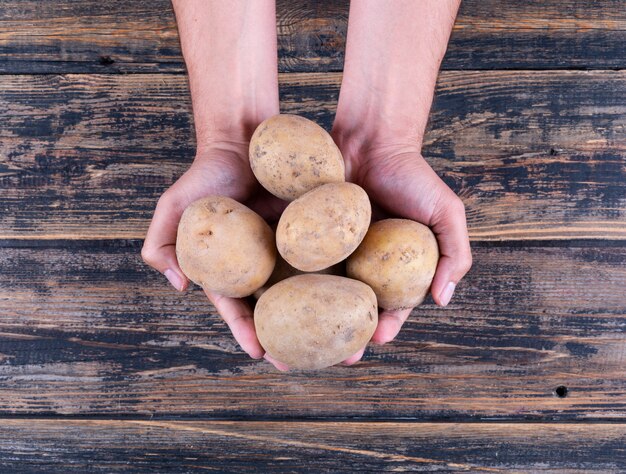 Aardappelen in een man handen op een donkere houten tafel