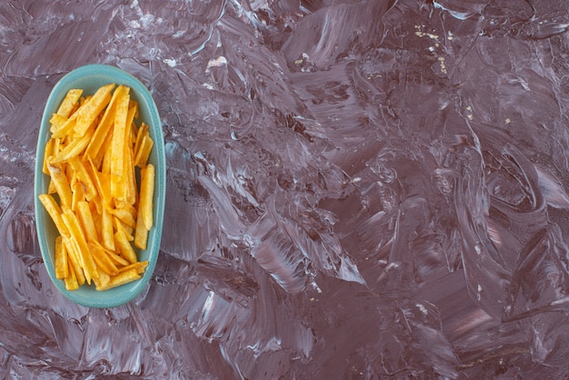 Aardappelfrietjes in een bord, op de marmeren tafel.