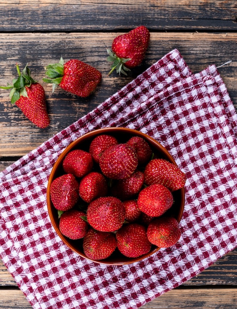 Aardbeien in een kom op een picknick doek en houten tafel. bovenaanzicht.