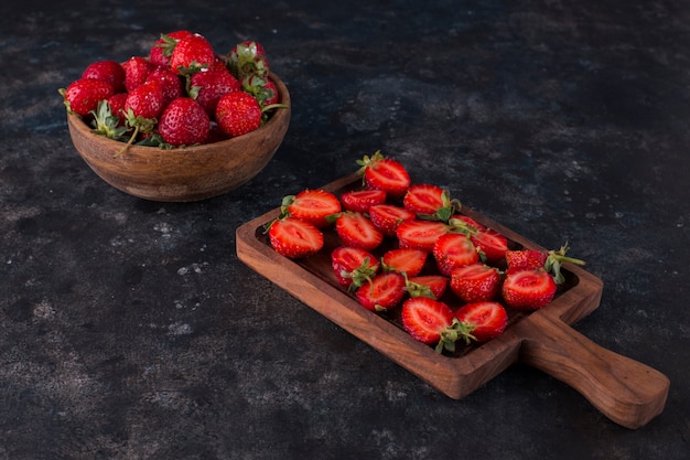 Aardbeien op een houten bord en in een bord