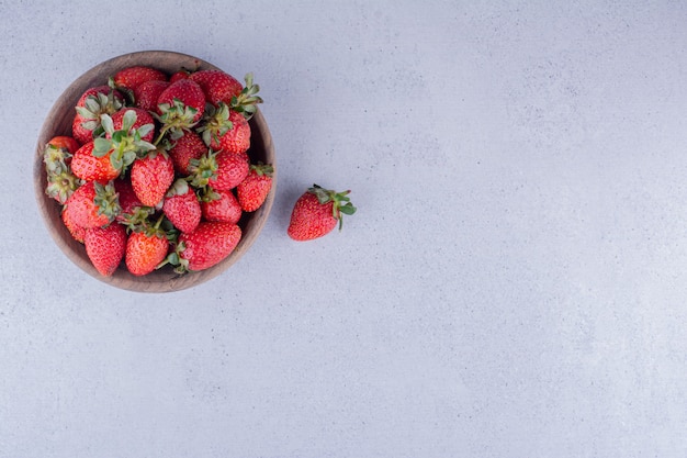 Aardbeien opgestapeld in een houten kom op marmeren achtergrond. Hoge kwaliteit foto