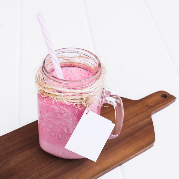 Gratis foto aardbeien smoothie met stro en label voor mock up op houten plank