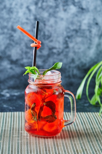 Aardbeienlimonade met ijs, stromunt in het donkere oppervlak