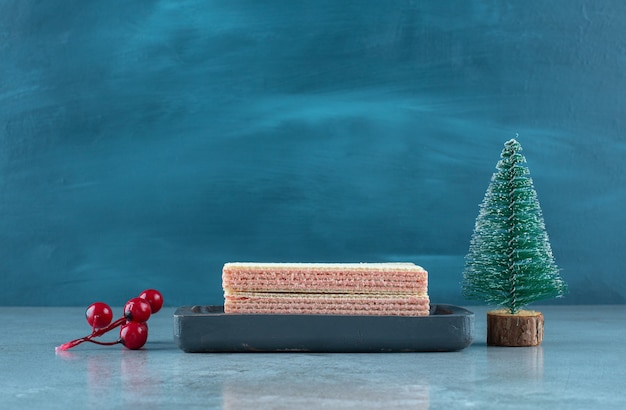 Aardbeienroom gevulde wafeltjes in een kleine bak naast kerstversieringen op marmeren oppervlak