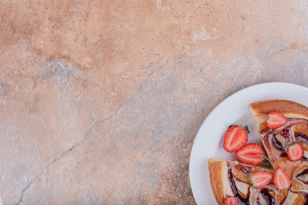 Aardbeientaart in een witte plaat met rond fruit.