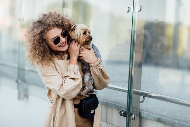 Aardige blonde vrouw met haar hond op een stad, concept van liefde voor huisdieren. Vriendschap mens en dier. Levensstijl.