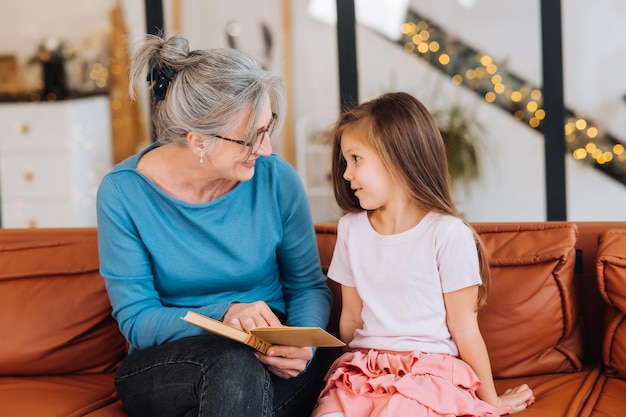 Aardige oma van een oudere vrouw die een verhaal voorleest aan kleindochter.