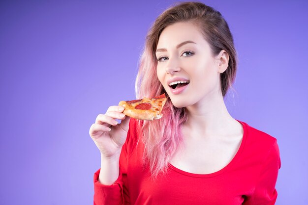 Aardige vrouw die een plak van pizza eet