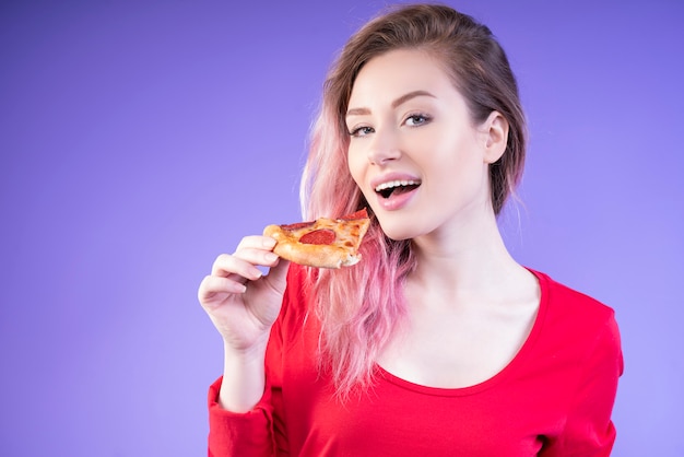 Aardige vrouw die een plak van pizza eet