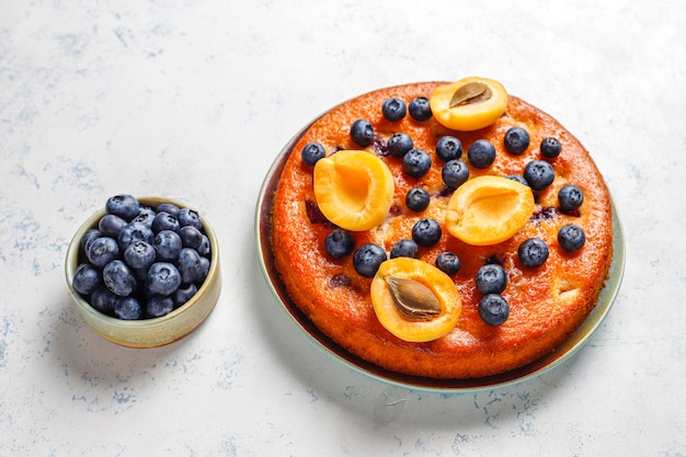 Gratis foto abrikozen- en bosbessencake met verse bosbessen en abrikozenvruchten.