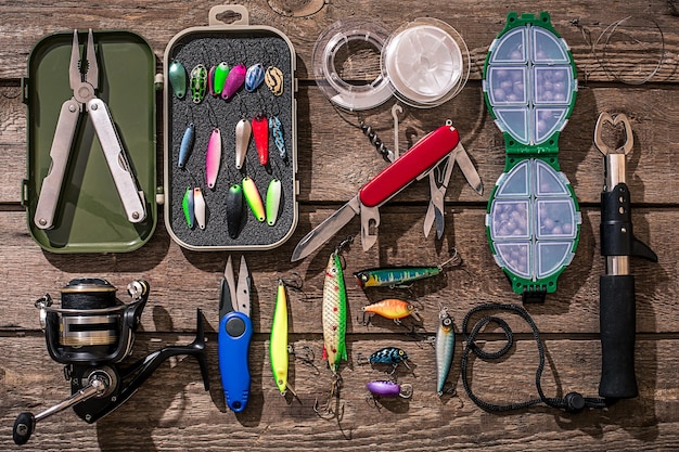 Accessoires voor het vissen op de achtergrond van hout. Haspel, vislijn, dobber, nethaken, kunstaas om te vissen. Bovenaanzicht. Stilleven. Kopieer ruimte