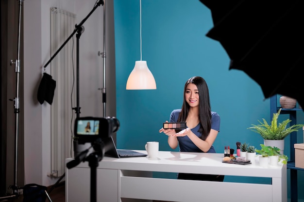 Gratis foto achter de schermen van aziatische influencer die make-uppaletrecensies filmt, beautytutorial opnemen voor sociale media-inhoud. vlogger-maker die cosmeticaproducten uitzendt met behulp van uitzendapparatuur