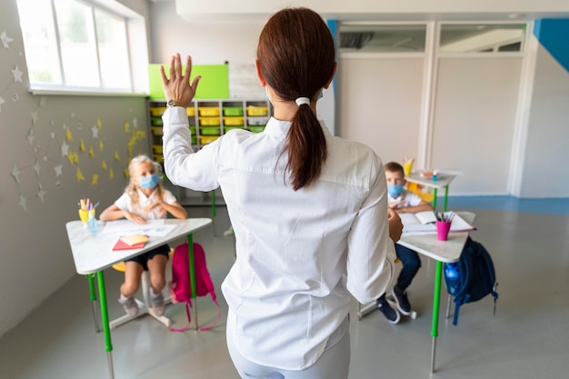 Achteraanzicht leraar wacht op een antwoord in de klas