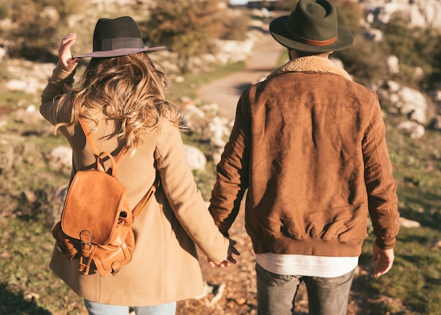 Achteraanzicht man en vrouw hand in hand buiten