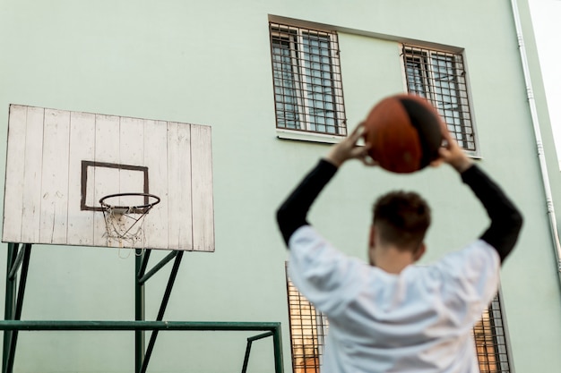 Gratis foto achteraanzicht man gooien van een basketbal